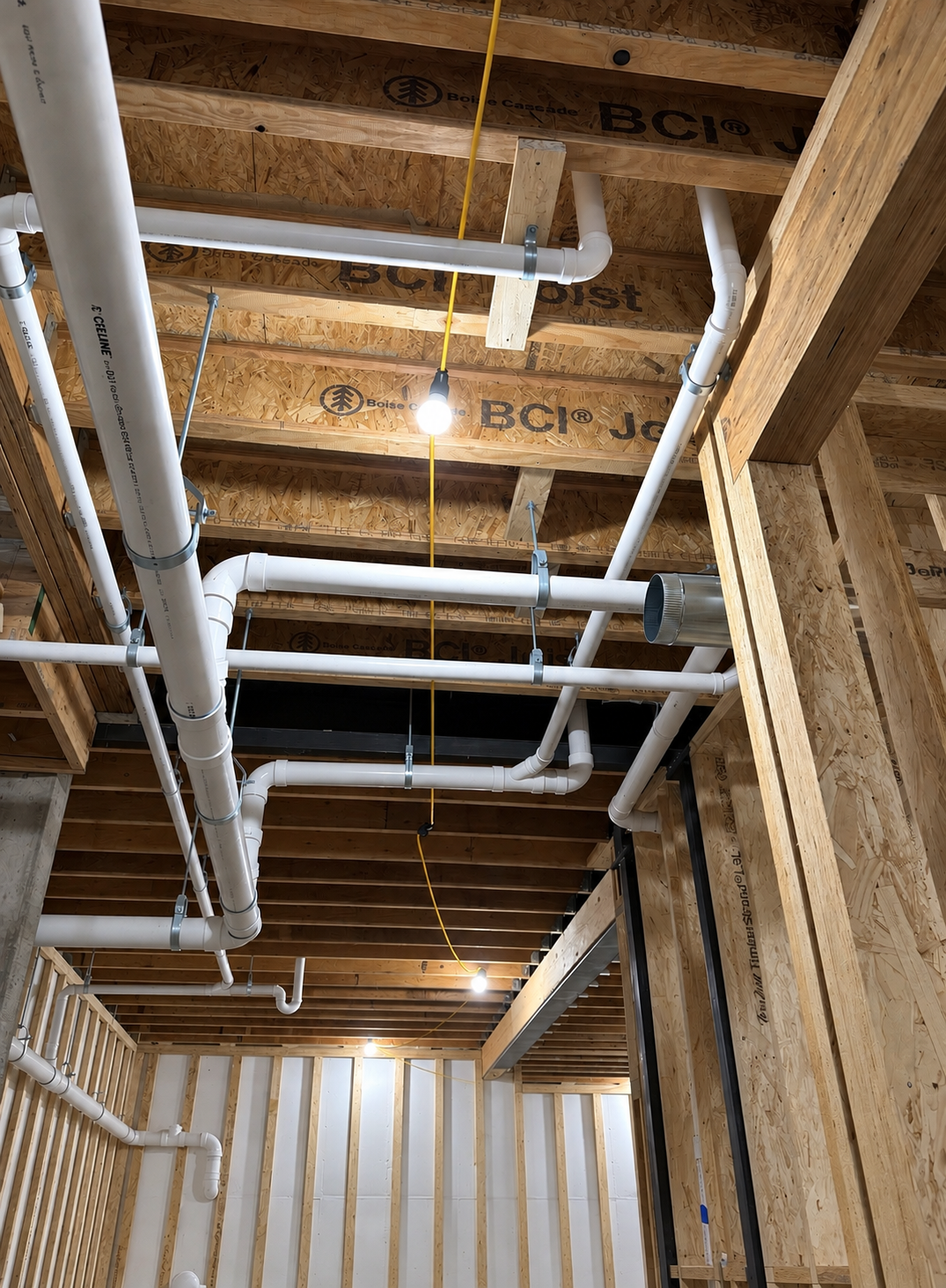Overhead PVC piping installed through new construction framing